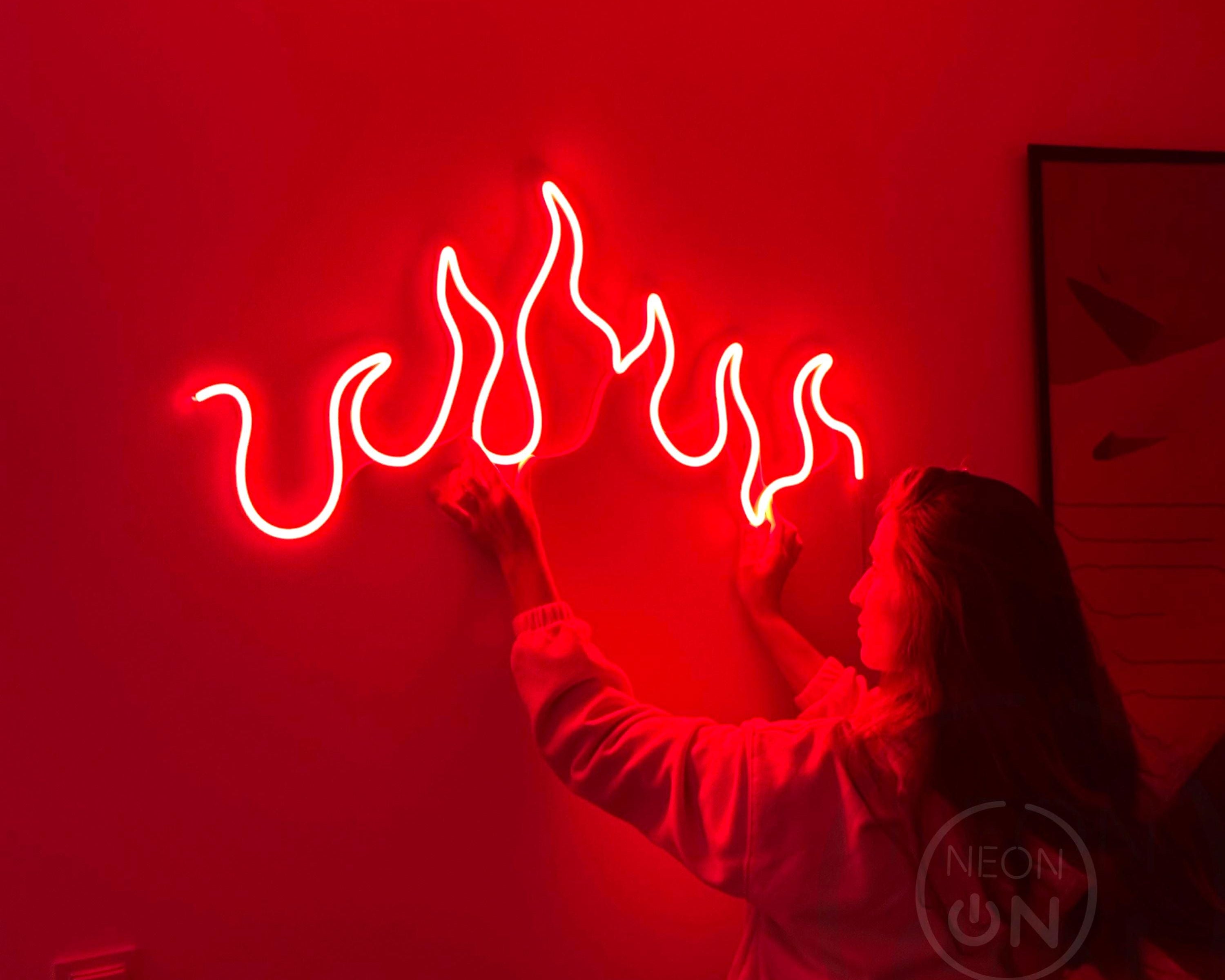 a woman holding up a neon sign with flames coming out of it