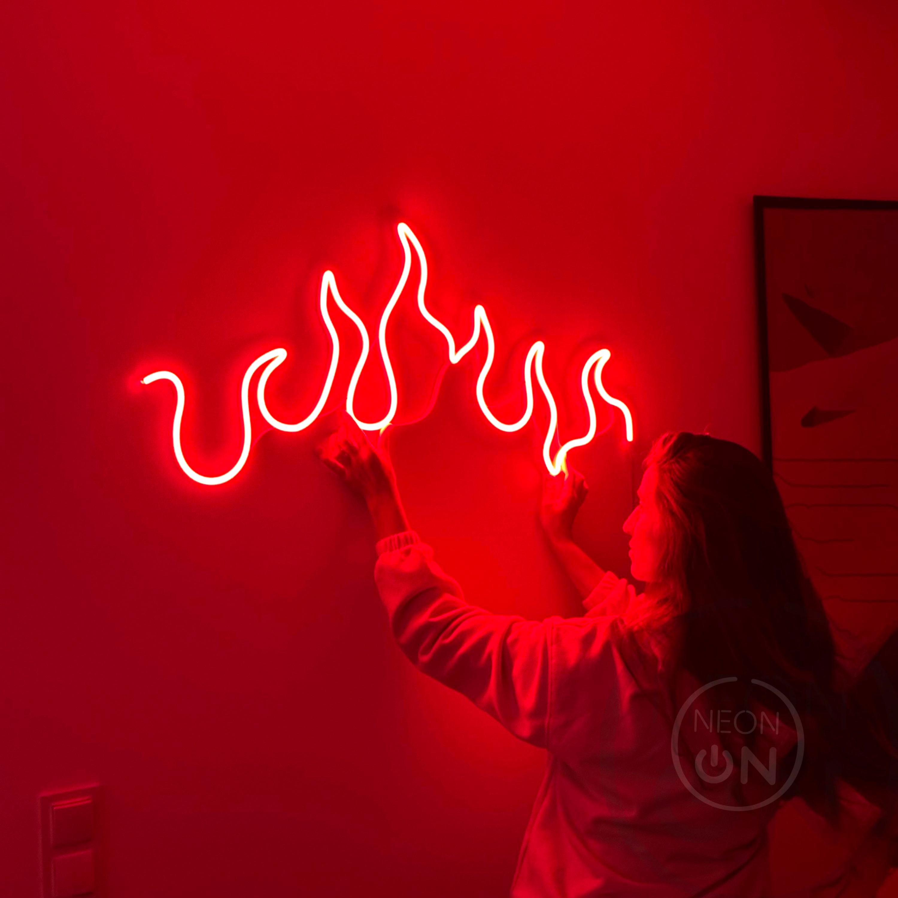 a woman holding up a neon sign with flames coming out of it